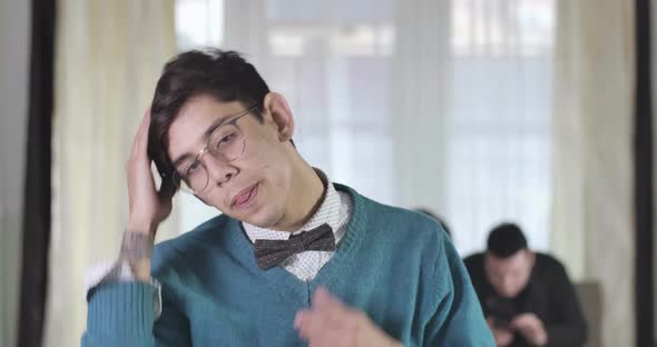 Portrait of Young Handsome Caucasian Boy Putting on Eyeglasses, Fixing Hair and Adjusting Bow Tie