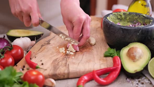 Making Guacamole Sauce  Woman Chopping Garlic on a Wooden Cutting Board