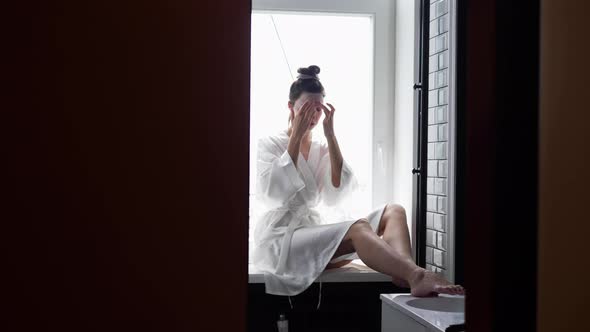 Woman in the Bathroom in Front of the Mirror Puts on a Rejuvenating Face Mask From Wrinkles