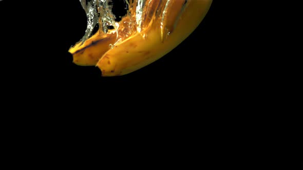 Super Slow Motion on a Black Background Bananas Fall Under the Water with Air Bubbles