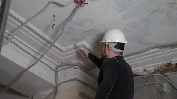 Fat Bearded Adult Man in Protective Helmet and Black Tight Fitting Clothing Remove Construction