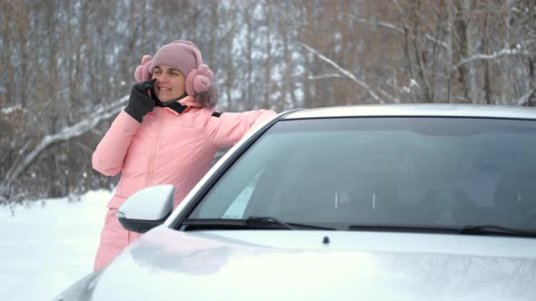 Woman Talks on Phone While Leans on Car in Winter