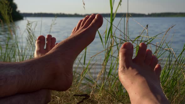 Bare Feet of Loving Man and Woman in Nature Near the River