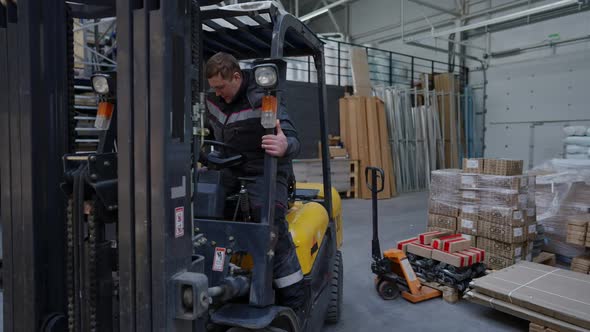 Wide Shot Professional Male Loader Operator Sitting in Vehicle in Warehouse in Slow Motion