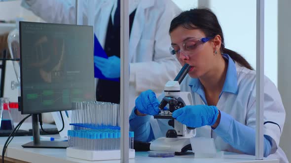 Chemist Adjusting Samples in a Petri Dish and Examining Under Microscope