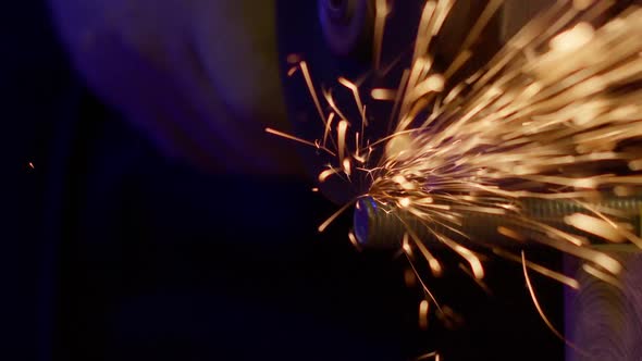 Locksmith in Overalls Cuts Metal with Angle Grinder. Sparks Fly in Slow Motion.