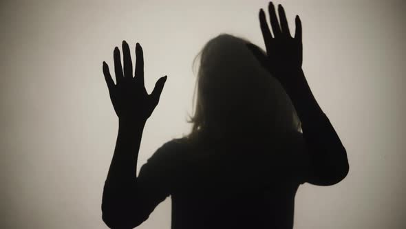 Silhouette of Woman Emerges From Smoke and Frightenedly Touches Glass with Palms