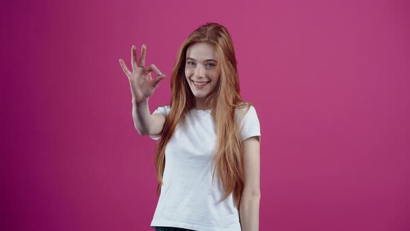 The Excited Redhaired Girl Cheerfully Shows the Ok Sign Delighted and Brings It Playfully to Her