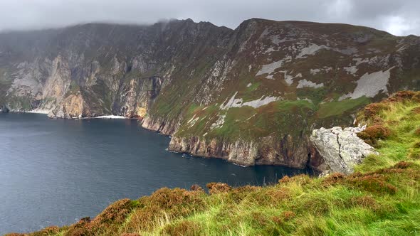 Panorama shot of giant cliff coastline of Ireland and calm blue Atlantic Ocean during mystic foggy d