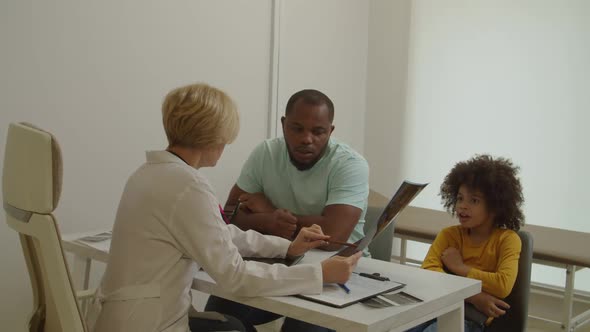 Pediatrician Holding Mri Scan Giving Medical Consultation to Father for Treatment Illness of Child