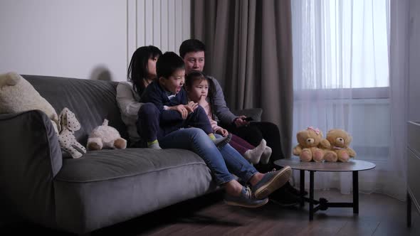 Friendly Asian Family Watching TV in Living Room