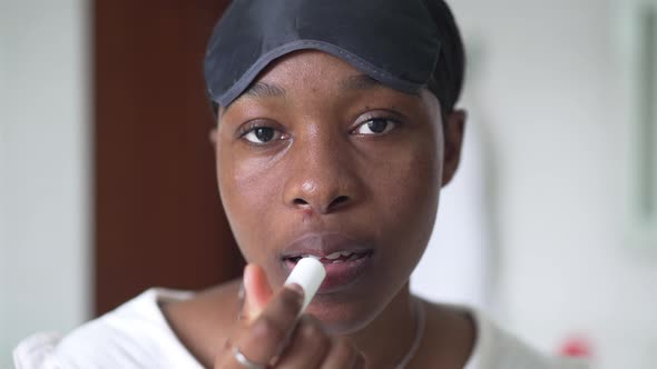 Positive African American Beautiful Woman Applying Hygienic Lipstick in Slow Motion Looking at