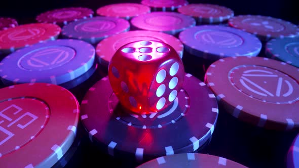 Red Dice Lying on a Pile of Casino Chips Spinning on a Black Background