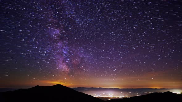 Starttrails Galaxia MilkyWay Above the Mountainsin the Valley the Bright Lights of the Night City