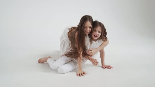 Little Girls with Long Hair in White Clothes Play Indulge and Fight