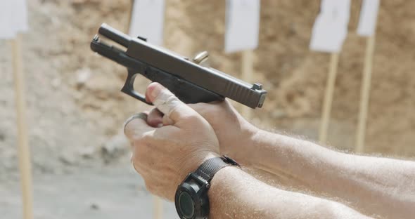 Slow motion close up shot of a man shooting a hand gun while moving backwards