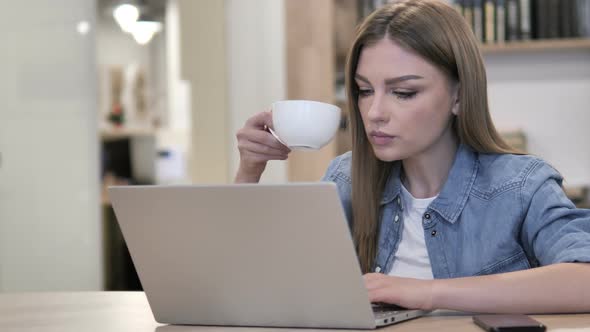 Creative Young Girl Drinking Coffee and Working on Laptop