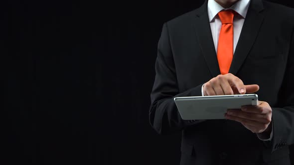 Man in Black Suit Working with a Tablet in His Hand Presses His Finger in Front of Himself. Mockup