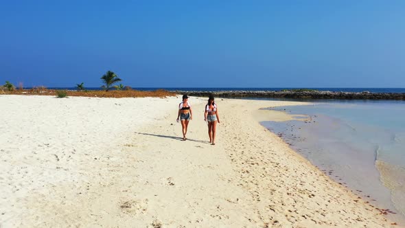 Girls enjoying life on tropical resort beach break by shallow water with bright sand background of K