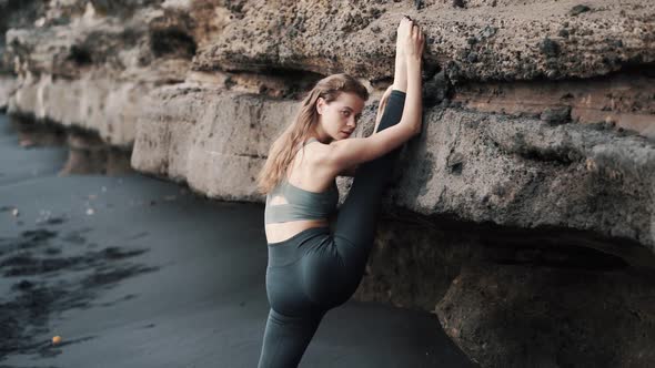 Young Woman Doing Stretching on Black Sand Beach Near Cliff Slow Motion