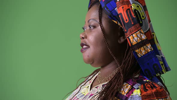 Overweight Beautiful African Woman Wearing Traditional Clothing Against Green Background