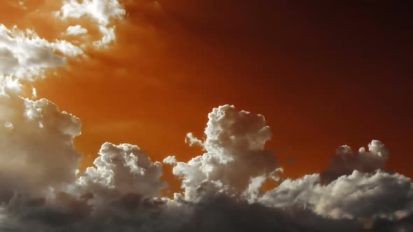 Fluffy clouds. 2 videos in 1 file.  White clouds moving through an orange and green sky.