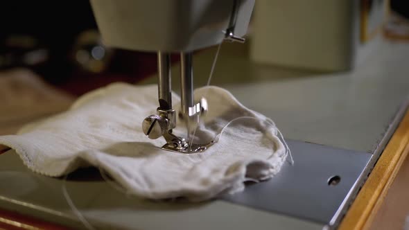 Sewing Machine Needle in Slow Motion. A Tailor Sews Homemade Face Mask of Fabric