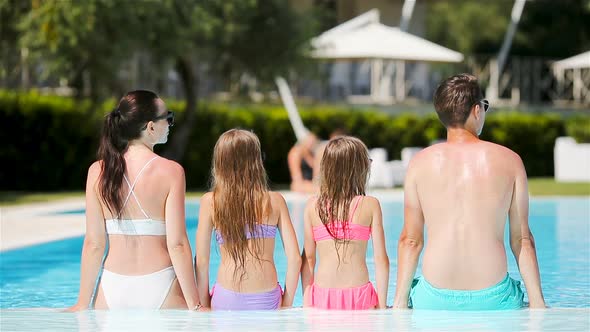 Happy Family of Four in Swimming Pool