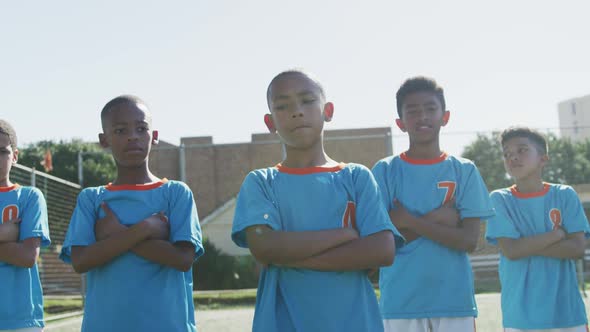 African American soccer kids in blue crossing arms and looking at camera in a sunny day