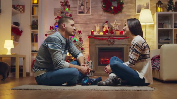 Beautiful Young Couple Looking at Each Other Sitting on the Carpet