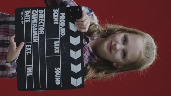 Girl Clapping Clapboard and Raising Eyebrows