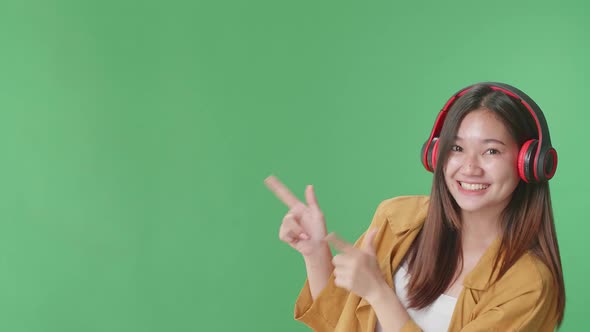 Woman Listening To Music And Dancing With A Smile Pointing In The Green Screen Studio