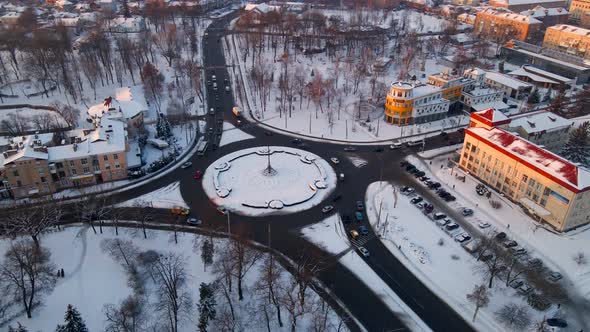 Aerial View of Roundabout Road with Circular Cars in Snow Covered Small European City at Winter