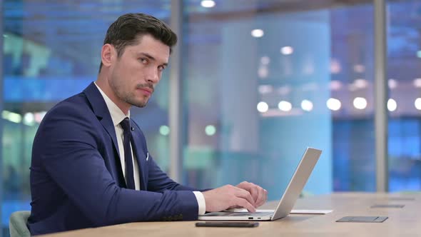 Working Businessman Looking at Camera in Office