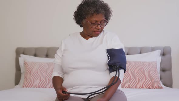 Mixed race woman checking her blood pressure. Social distancing and self isolation in quarantine