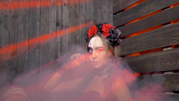 Portrait of a Lovely Woman with Halloween Makeup on Her Face in Red Rays of Light is Enveloped in