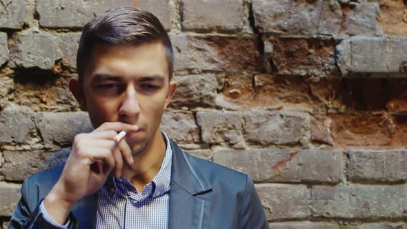 Young Frustrated Businessman Smokes in an Abandoned House. Concept - Stress, Depression, Probblemy