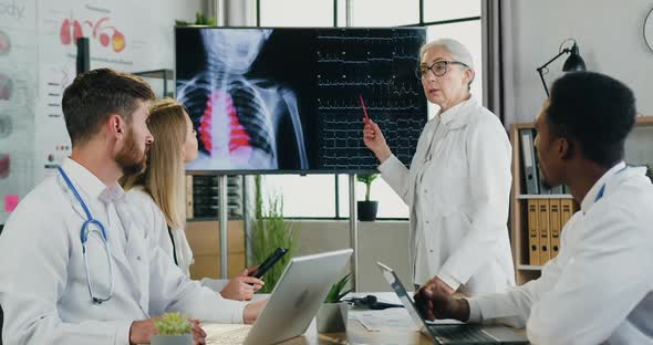 Multiethnic Male and Female Doctors Examining Results of Patient's Chest X-ray and Heartbeat