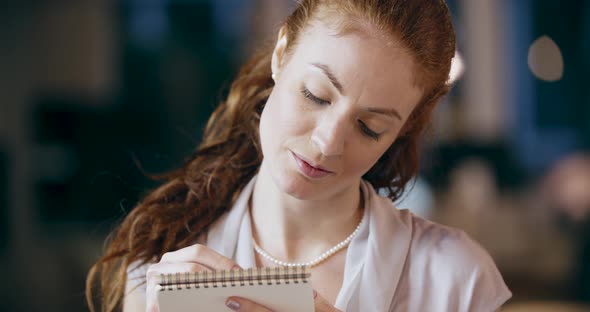 Redhead Woman Writing on Notepad Portrait
