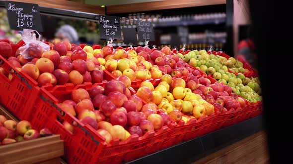 Fruits with Price Tags on a Shop Window in a Supermarket and Shoppers Walking By.