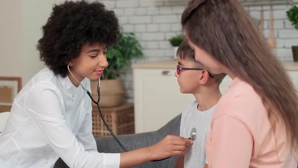 Afro American Woman Doctor Listens to Child's Lungs Using Stethoscope During Checkup