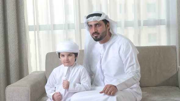 Excited Arab family. Happy Arabic father and son celebrate the win of their team. Middle East father