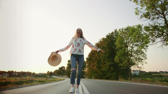 Beautiful Young Female with Nice Hat Smiling and Running on Asphalt Road