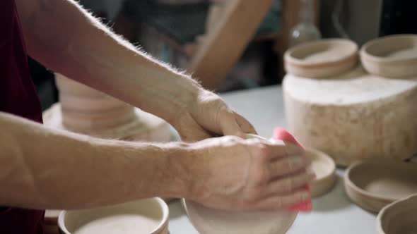 Man Hands Makes Clay Plates in Pottery Workshop Top Close Up View Focus on Stained Hand