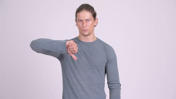 Angry Man Giving Thumbs Down Against White Background