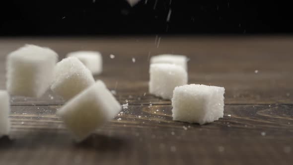 sugar cubes fall on a wooden surface