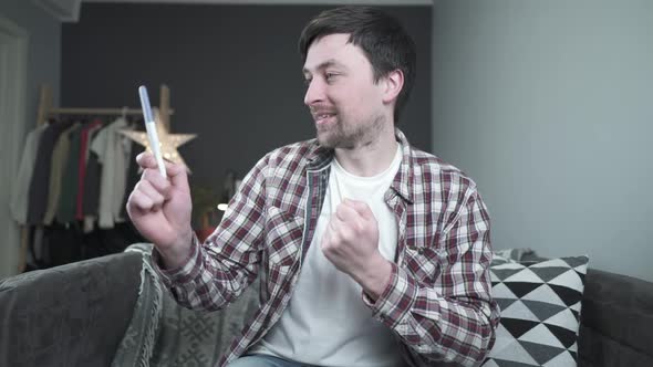 Young Caucasian Man Holding Pregnancy Test in His Hands Very Excited and Happy with Result and