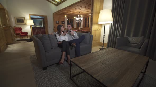 A man and woman couple drinking red wine in a luxury resort hotel room