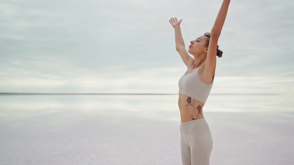 Beautiful Slender Woman in Leggins and Top Meditating and Practicing Yoga Outdoors