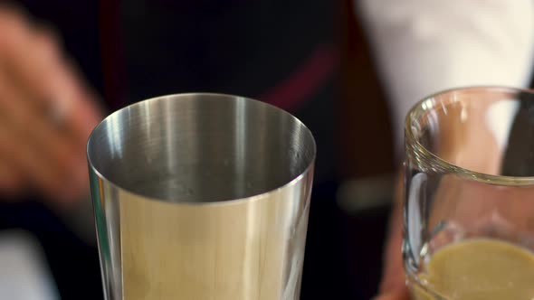 The Bartender Is Preparing an Alcoholic Cocktail Using a Strainer.